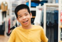 Disabled Child On Wheelchair Having Fun Shopping For Clothes Tha