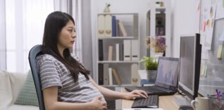 Pregnant Woman Working On Computer At Table