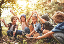 Stock photo of half a dozen kids sitting in the woods looking happy.