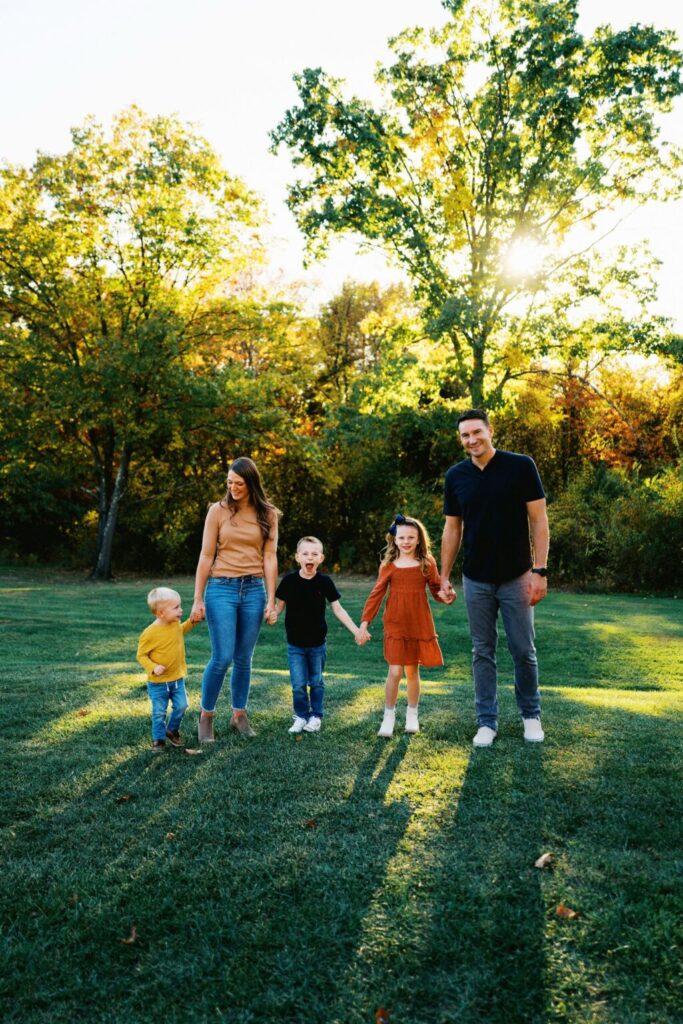 Family holding hounds in a grassy outdoor setting