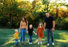 Family holding hounds in a grassy outdoor setting