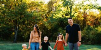 Family holding hounds in a grassy outdoor setting