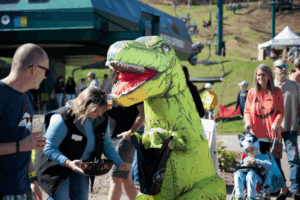 A person in a dinosaur costume at a fall festival
