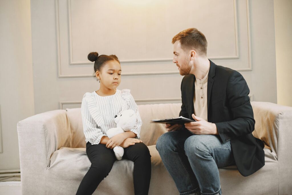 A therapist speaking to a child with a teddy bear