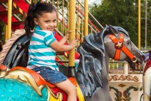 Young girl riding a horse on a carousel