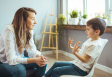 Young female psychologist working with little boy in office.