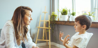 Young female psychologist working with little boy in office.