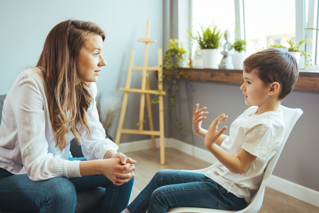 Young female psychologist working with little boy in office. 