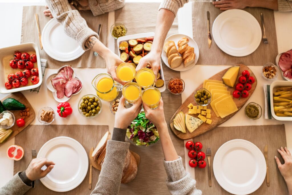 People toasting with orange juice over a brunch table