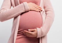 panoramic crop of pregnant woman touching belly isolated on white